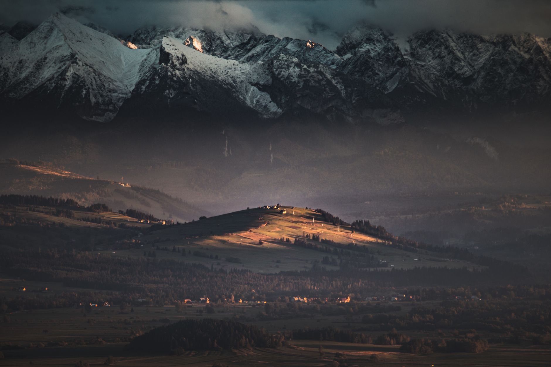 Majestic view of Vysoké Tatry mountains at twilight, illuminated valleys and snow-capped peaks in Slovakia.
