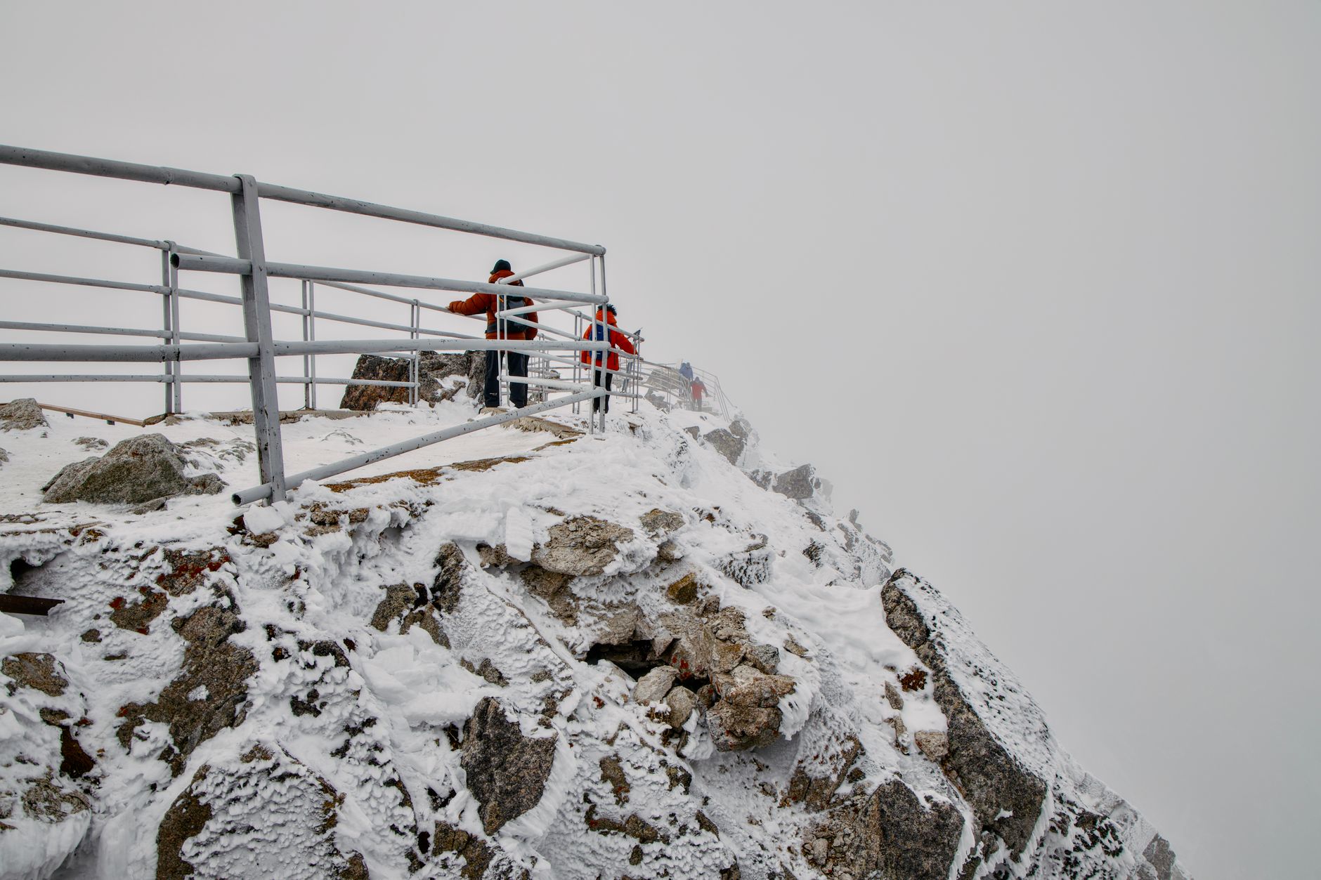 Adventurers exploring snow-covered peaks in Vysoké Tatry, Slovakia, on a foggy day.