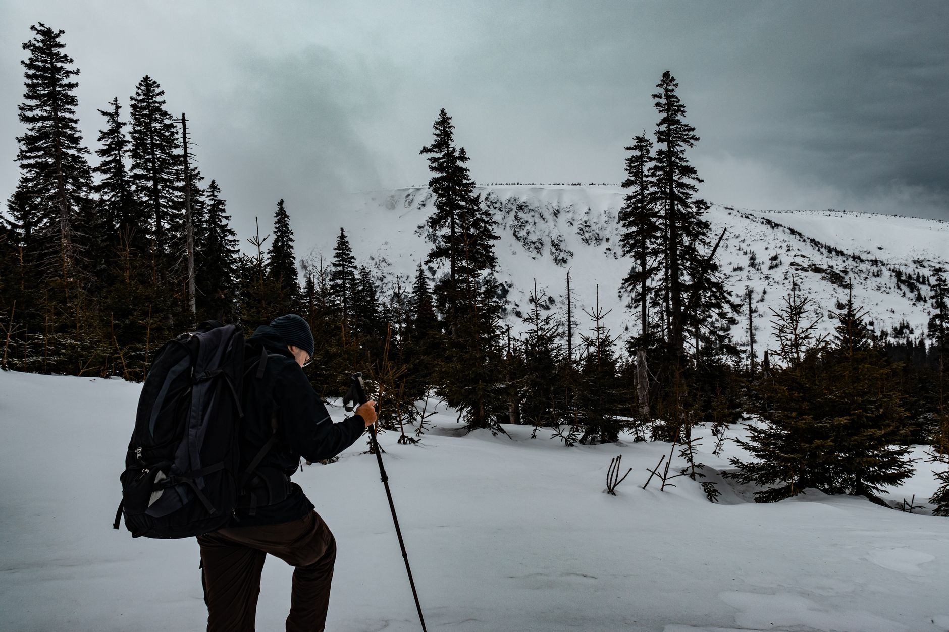 A hiker explores the snowy landscape of Karkonosze, Poland, during winter.