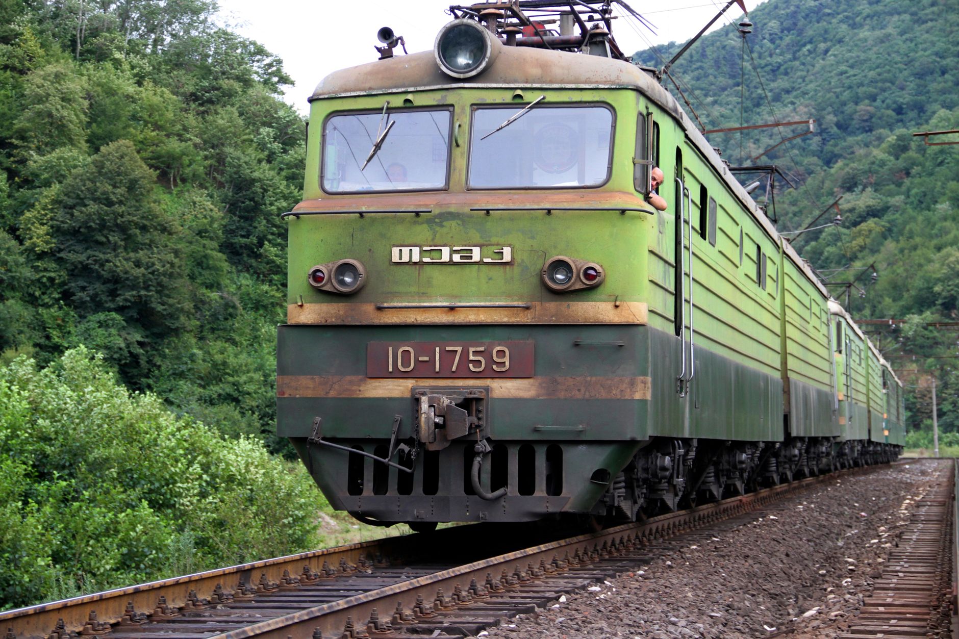 A classic Soviet-era locomotive traveling through lush forests in Kharagauli, Georgia.