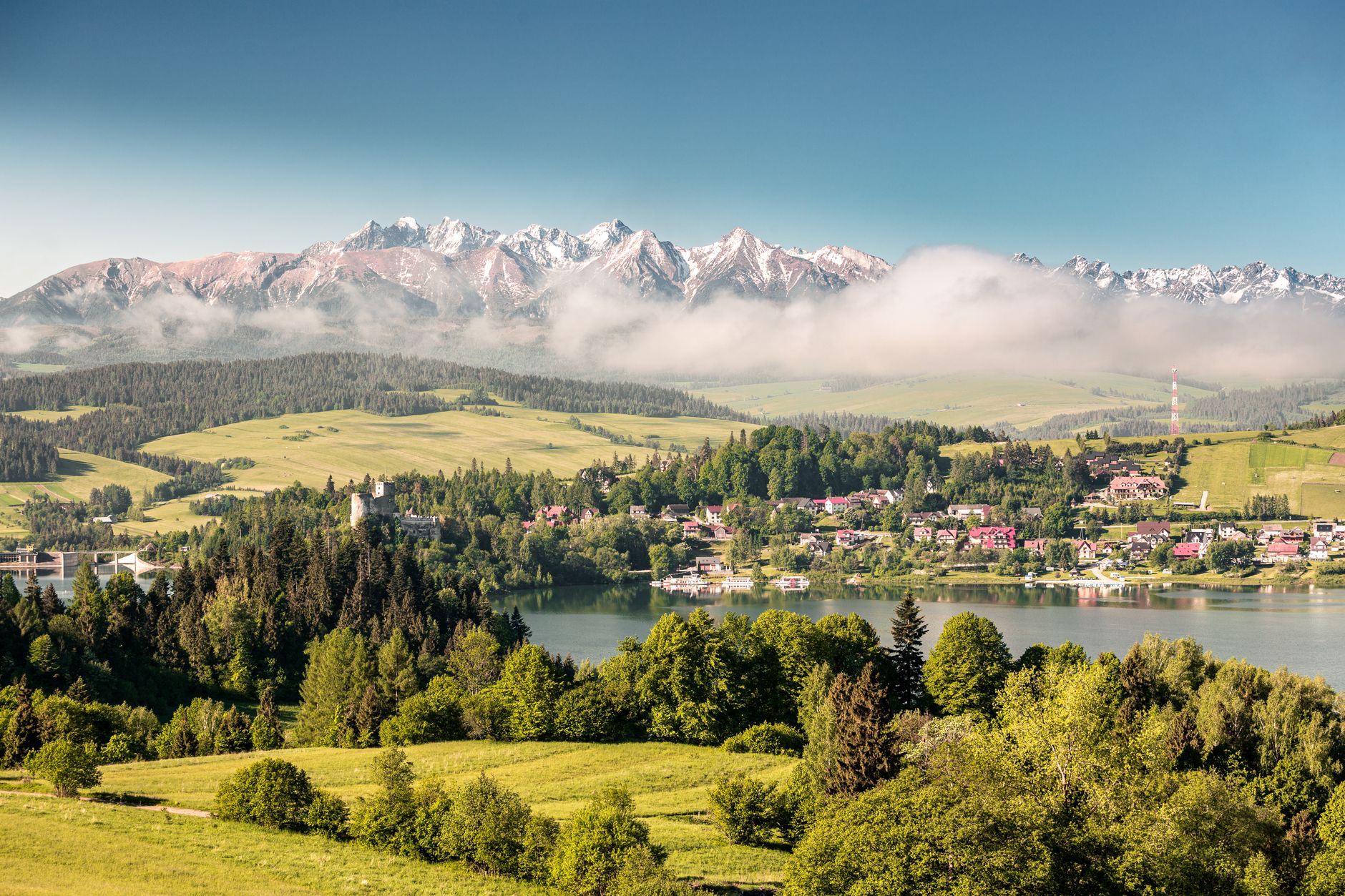 Breathtaking landscape of the Tatra Mountains and lush greenery near a serene lake in Poland.