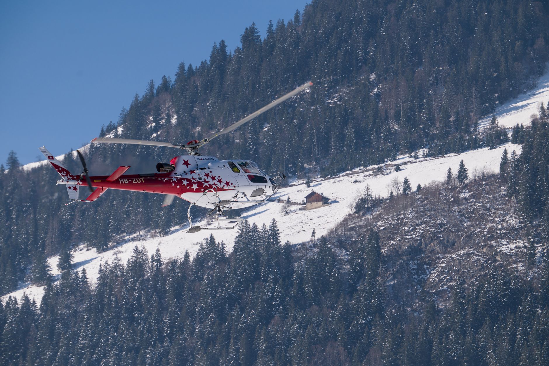 A helicopter soars above the snow-covered slopes in the picturesque Swiss Alps.