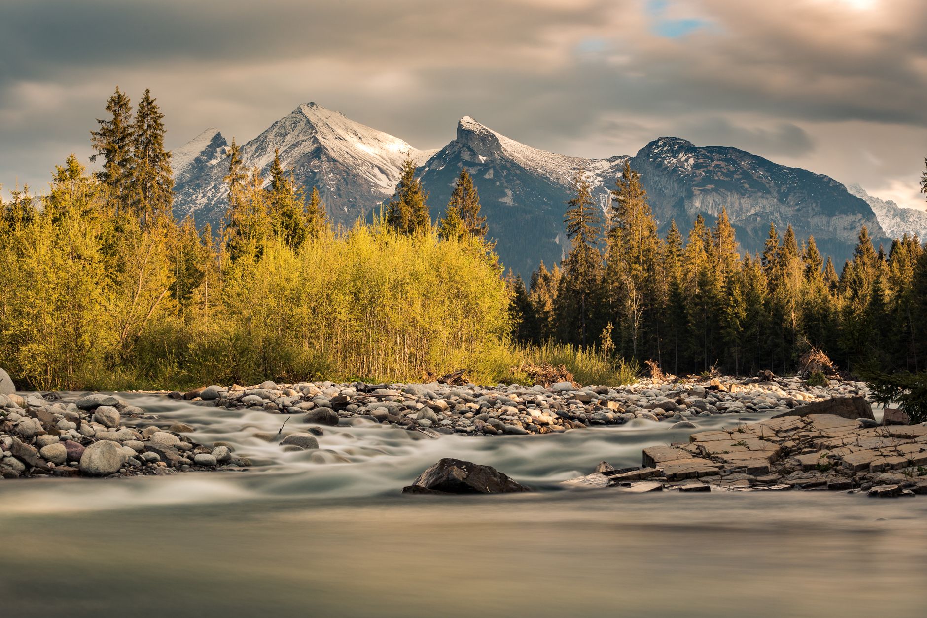 Beautiful landscape of Tatra Mountains with a flowing river and evergreen forest in Poland.