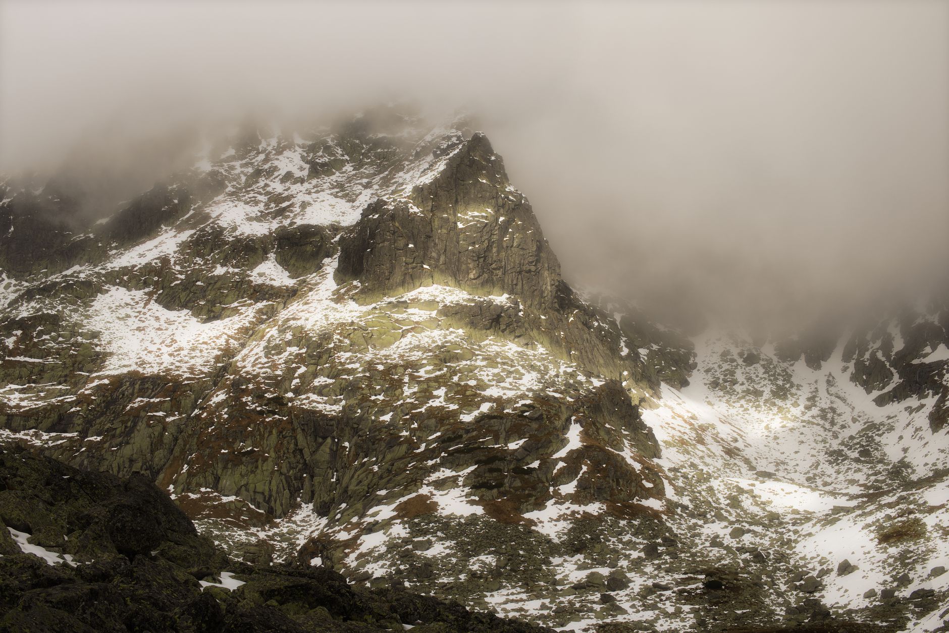 Breathtaking view of Slovakia's Tatra Mountains with mist-covered peaks and light snow.