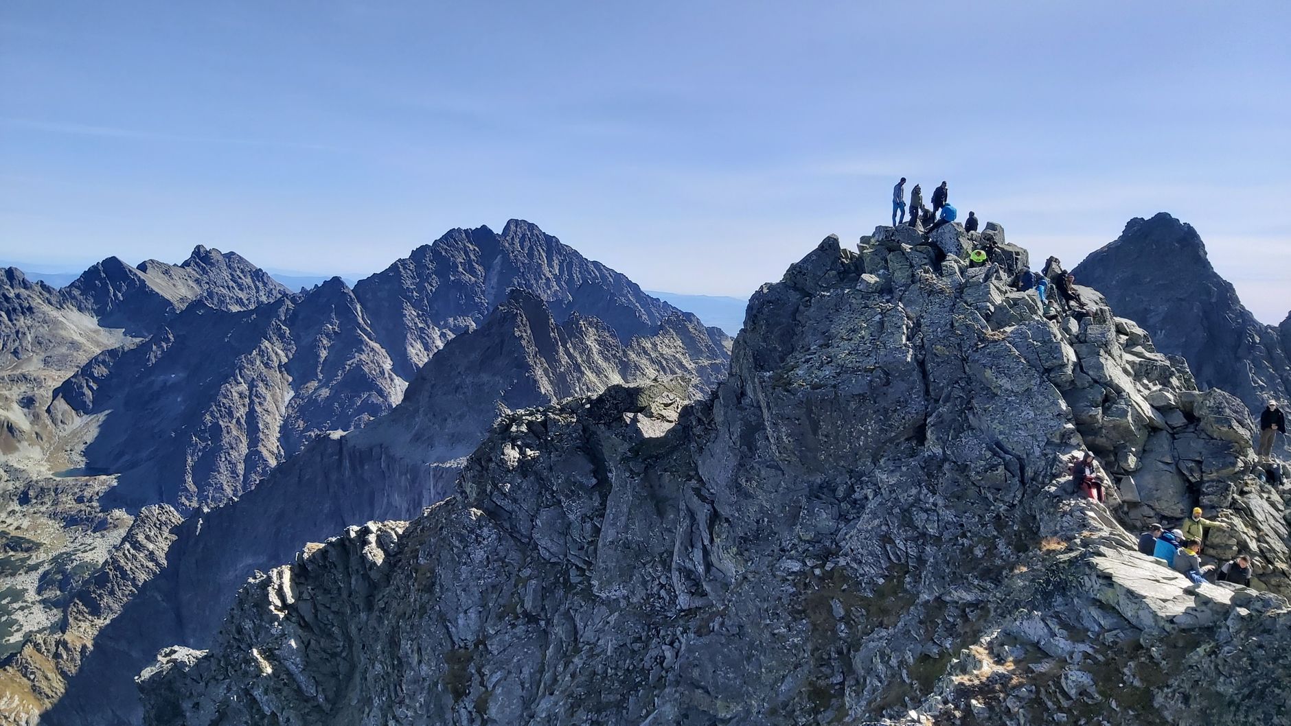 Group of hikers exploring a rocky mountain peak in Poland's Tatra Mountains on a clear day.