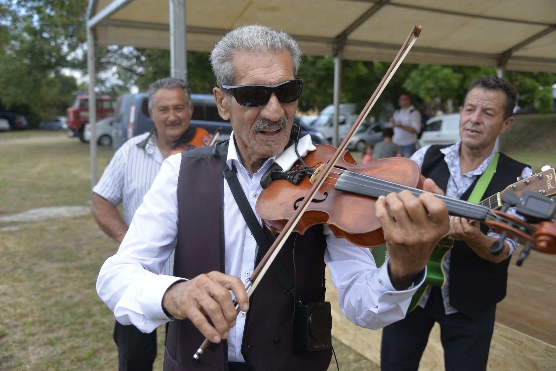 Elderly musicians perform traditional folk music outdoors in Szatmárcseke, Hungary.