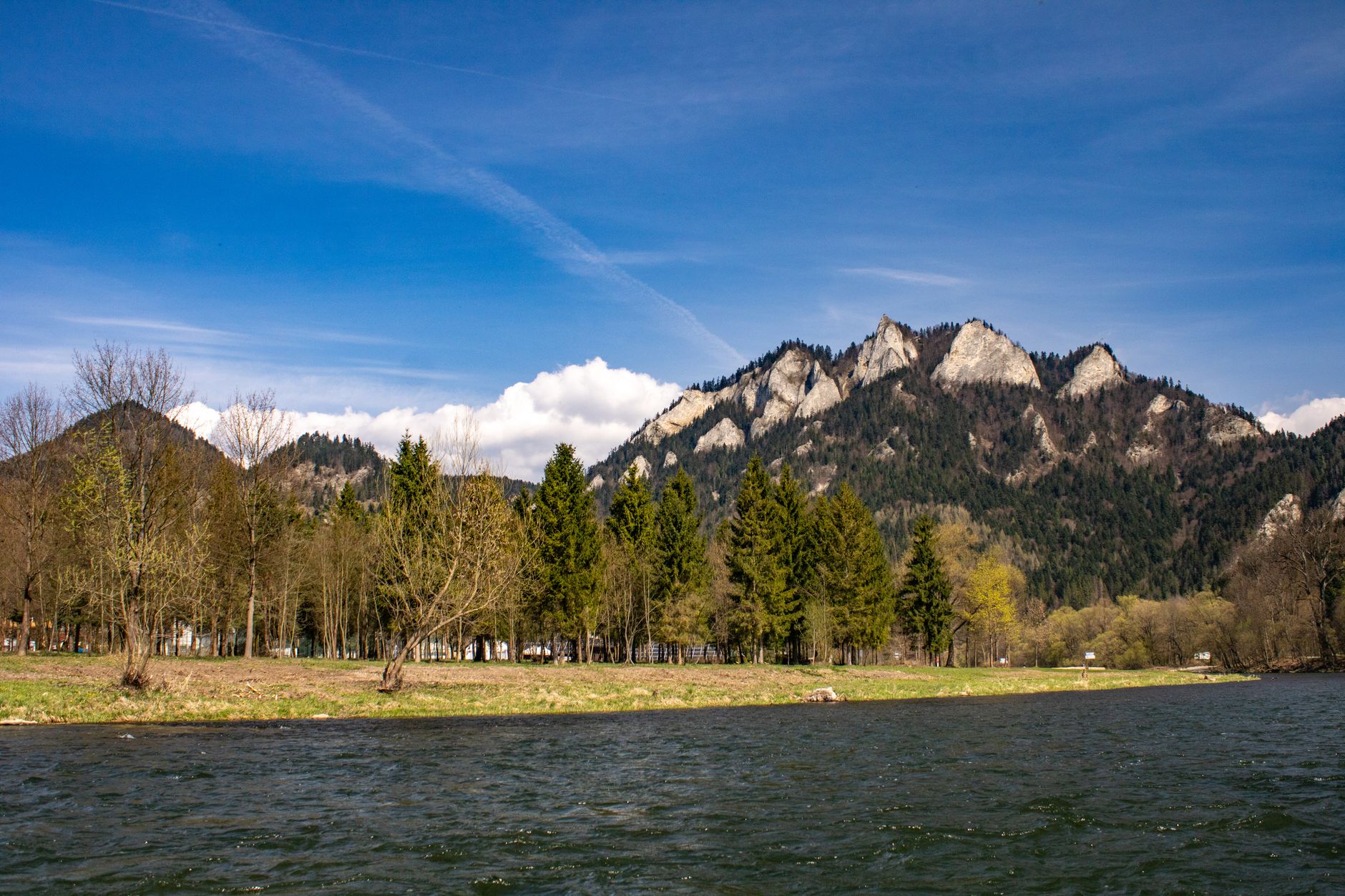 Majestic landscape of Three Crowns Mountain with trees and a river in springtime.