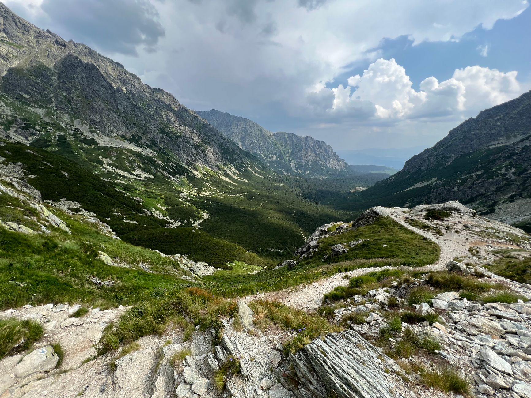 Breathtaking view of the High Tatras mountain valley with a scenic hiking trail and lush greenery.