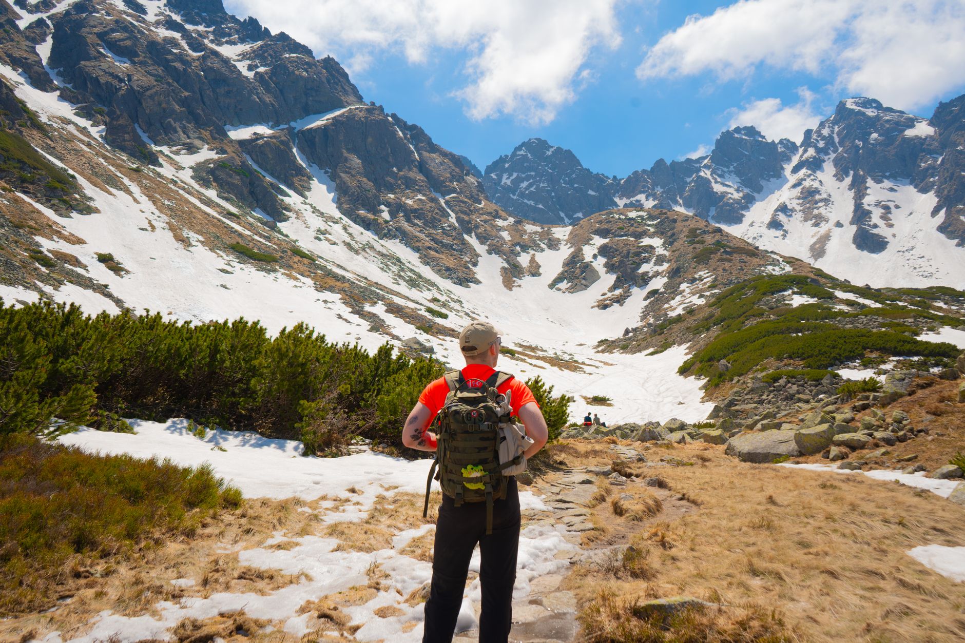 Hiker explores the scenic pathways of Tatra Mountains under a clear sky.