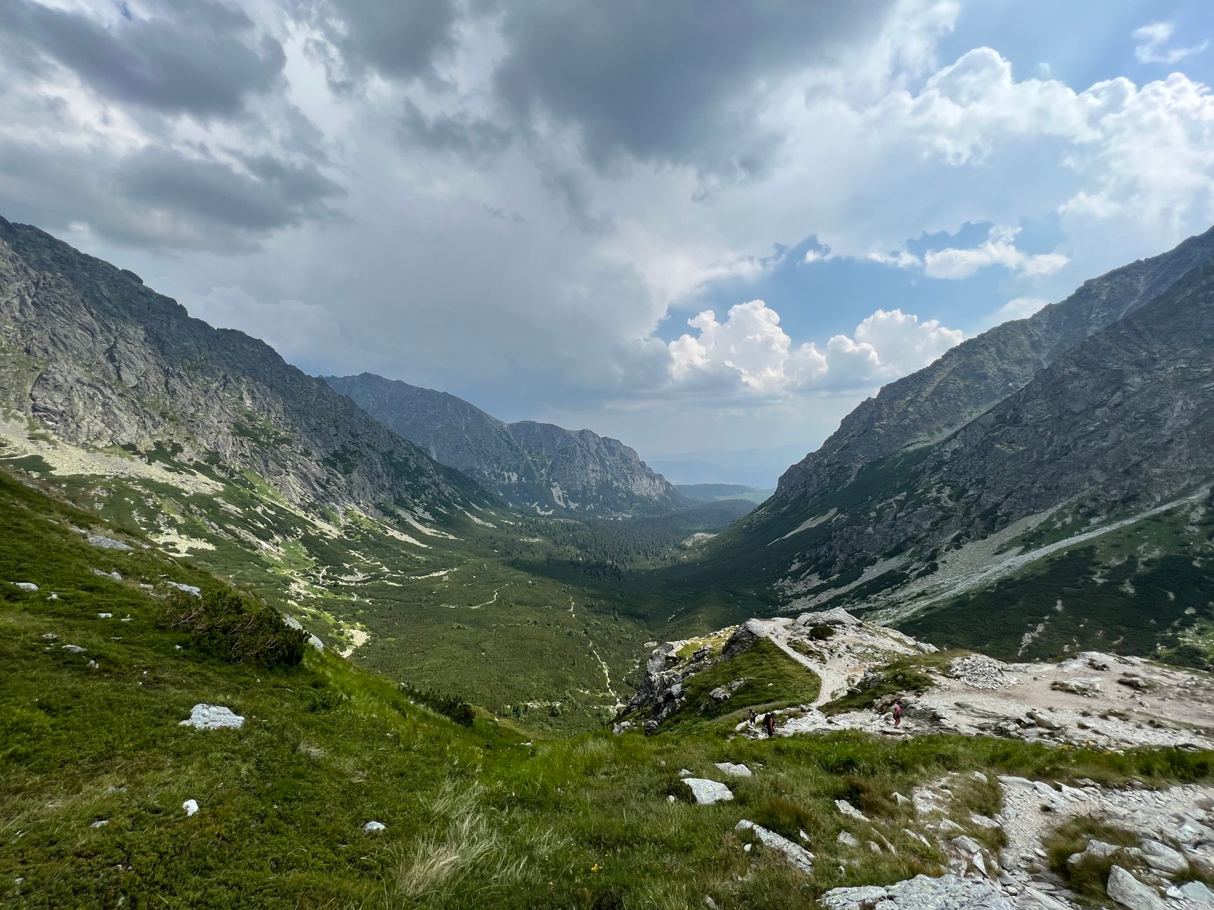 Majestic mountain valley in the High Tatras with lush greenery under a dramatic sky.