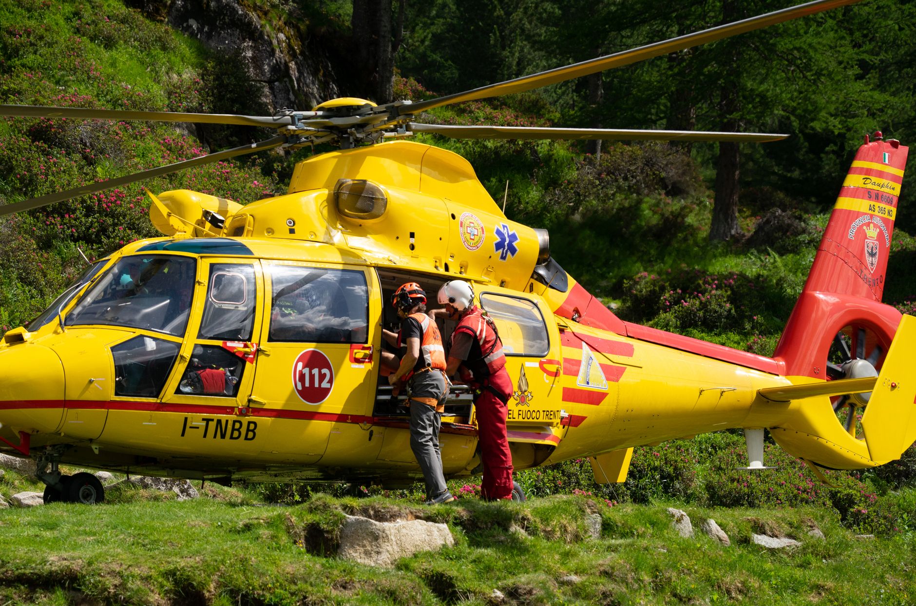 Emergency rescue team preparing helicopter in mountainous rural area.