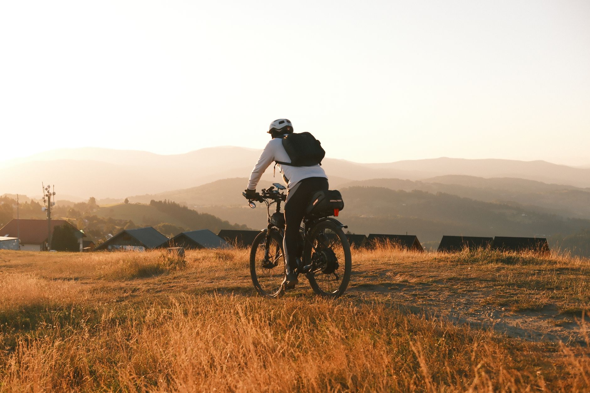Cyclist explores scenic mountain path in Poland during sunset, capturing nature's beauty.