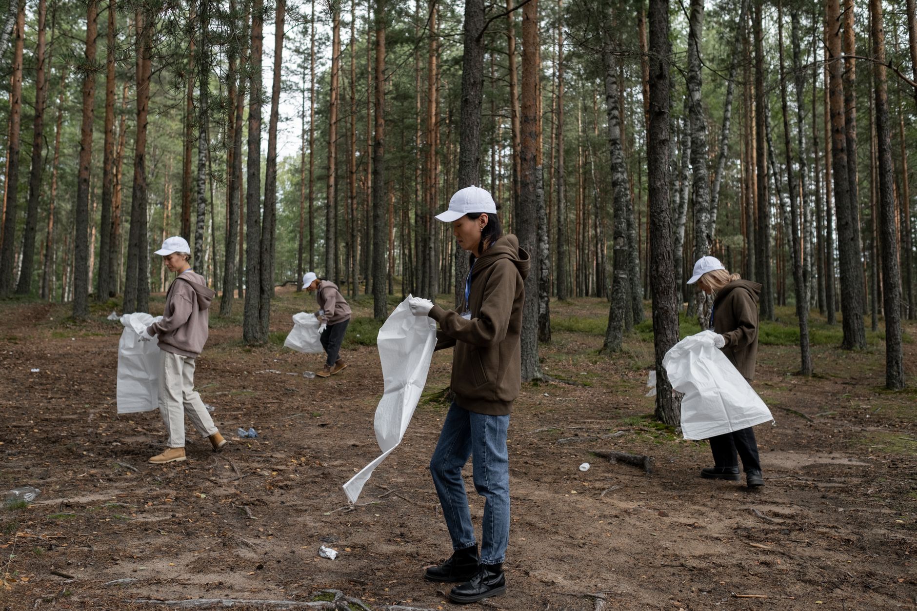 Group of volunteers cleaning up litter in a forest, promoting environmental conservation and community effort.