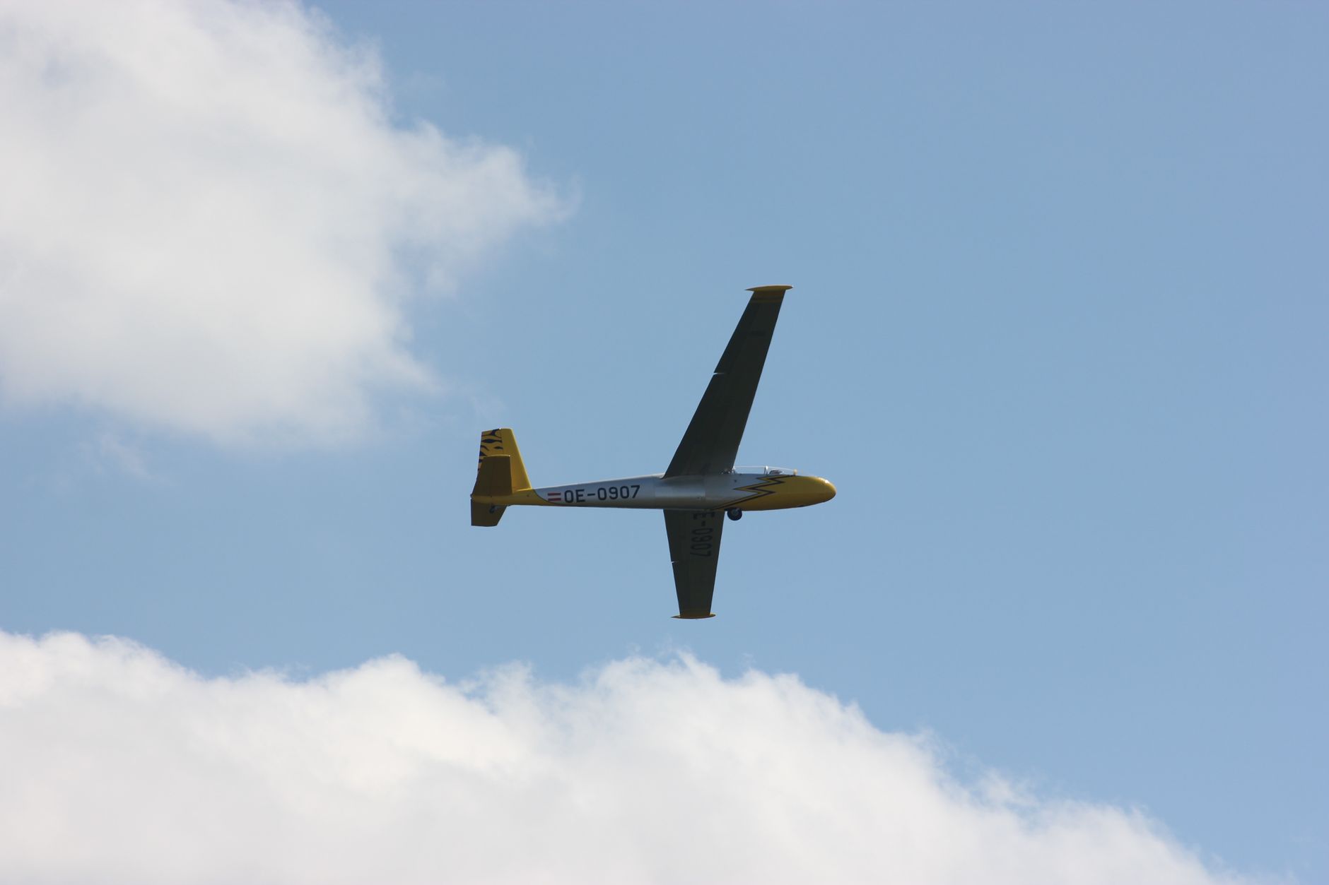 A glider aircraft gracefully soaring through a clear blue sky on a sunny day.