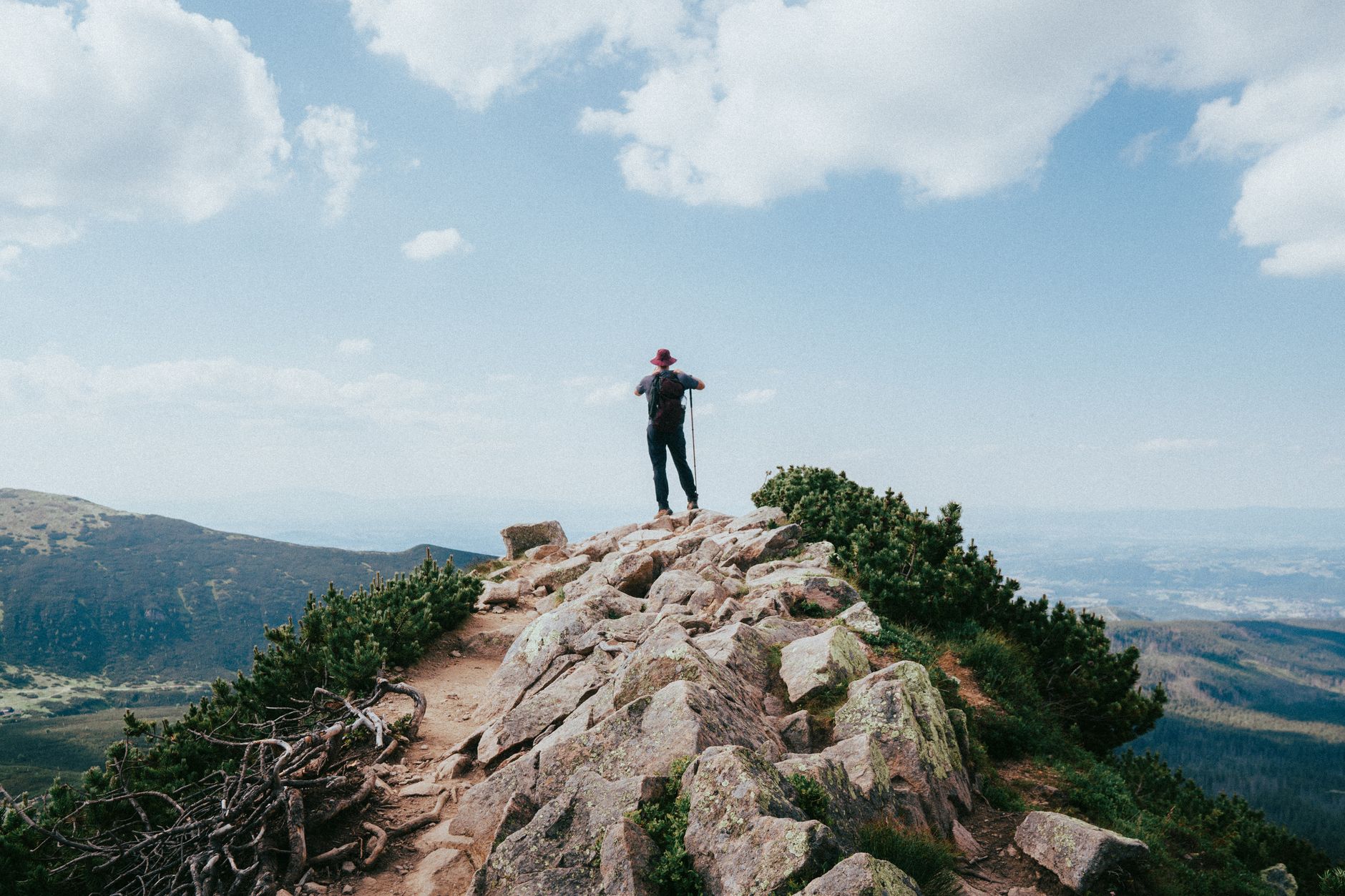 A lone hiker with a backpack enjoying a panoramic view in the Tatra Mountains.
