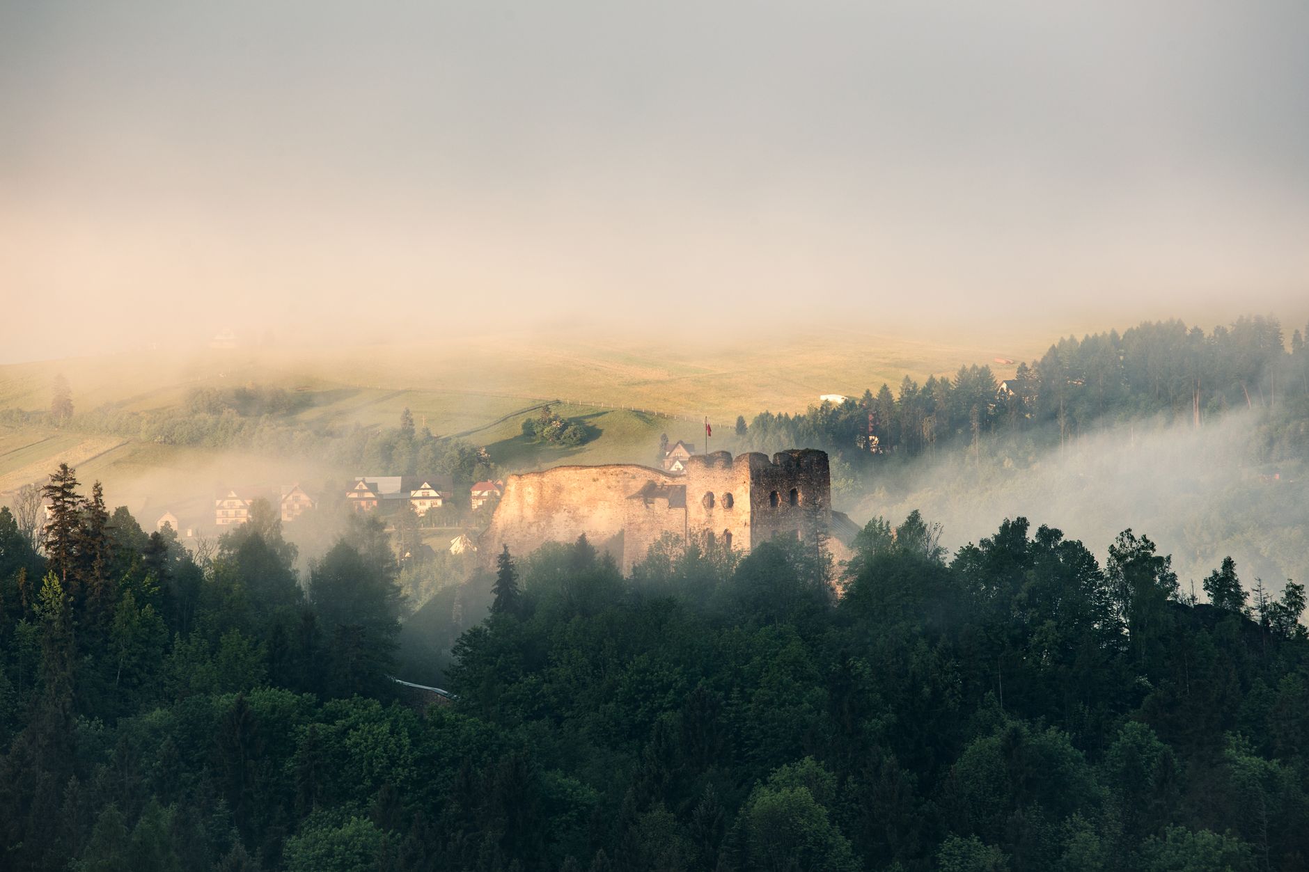 A captivating view of ancient ruins amidst misty forests and rolling hills in the Tatra Mountains.
