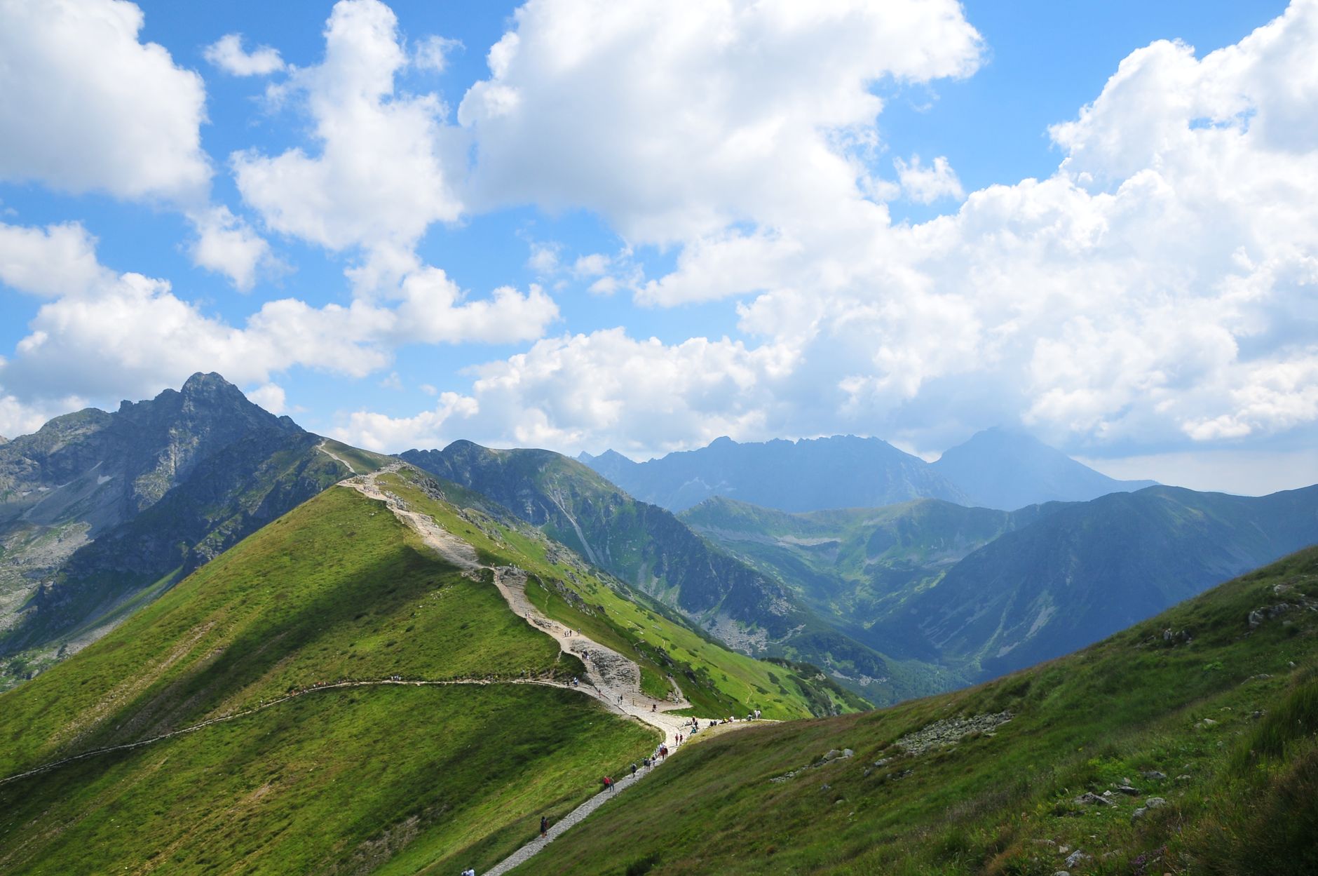 A scenic view of the Tatra Mountains and hiking trail in Zakopane, Poland on a vibrant summer day.