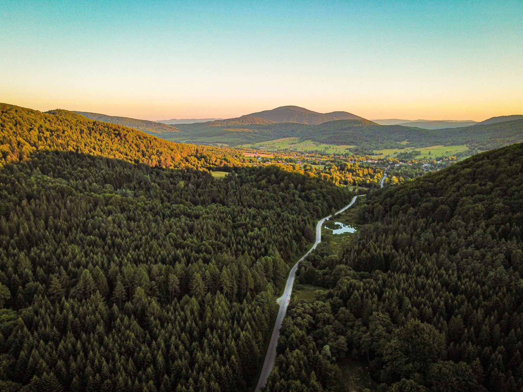 Stunning aerial view of Wysowa-Zdrój, showcasing lush forests and rolling hills during a summer sunset.