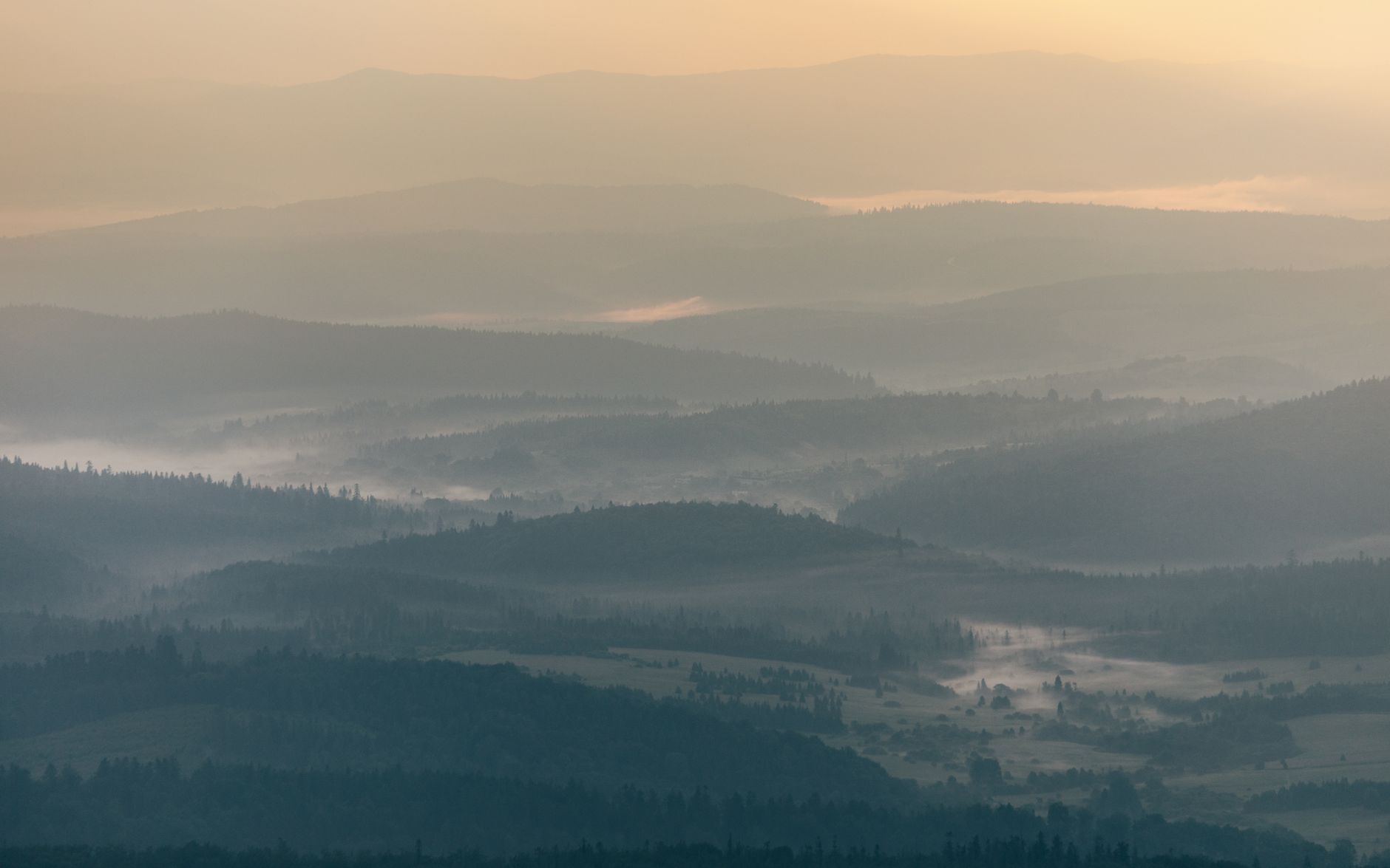 Serene view of misty mountain ranges in Podkarpackie Voivodeship, Poland at sunrise.