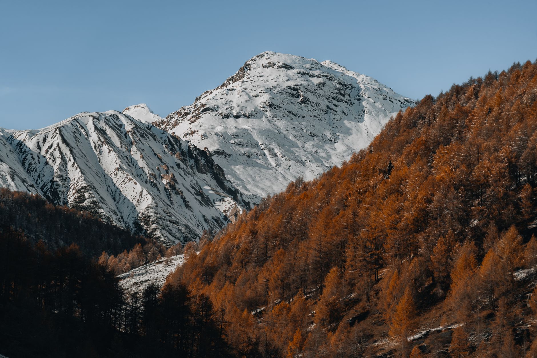 Stunning view of a snowy mountain peak surrounded by vibrant autumn foliage.