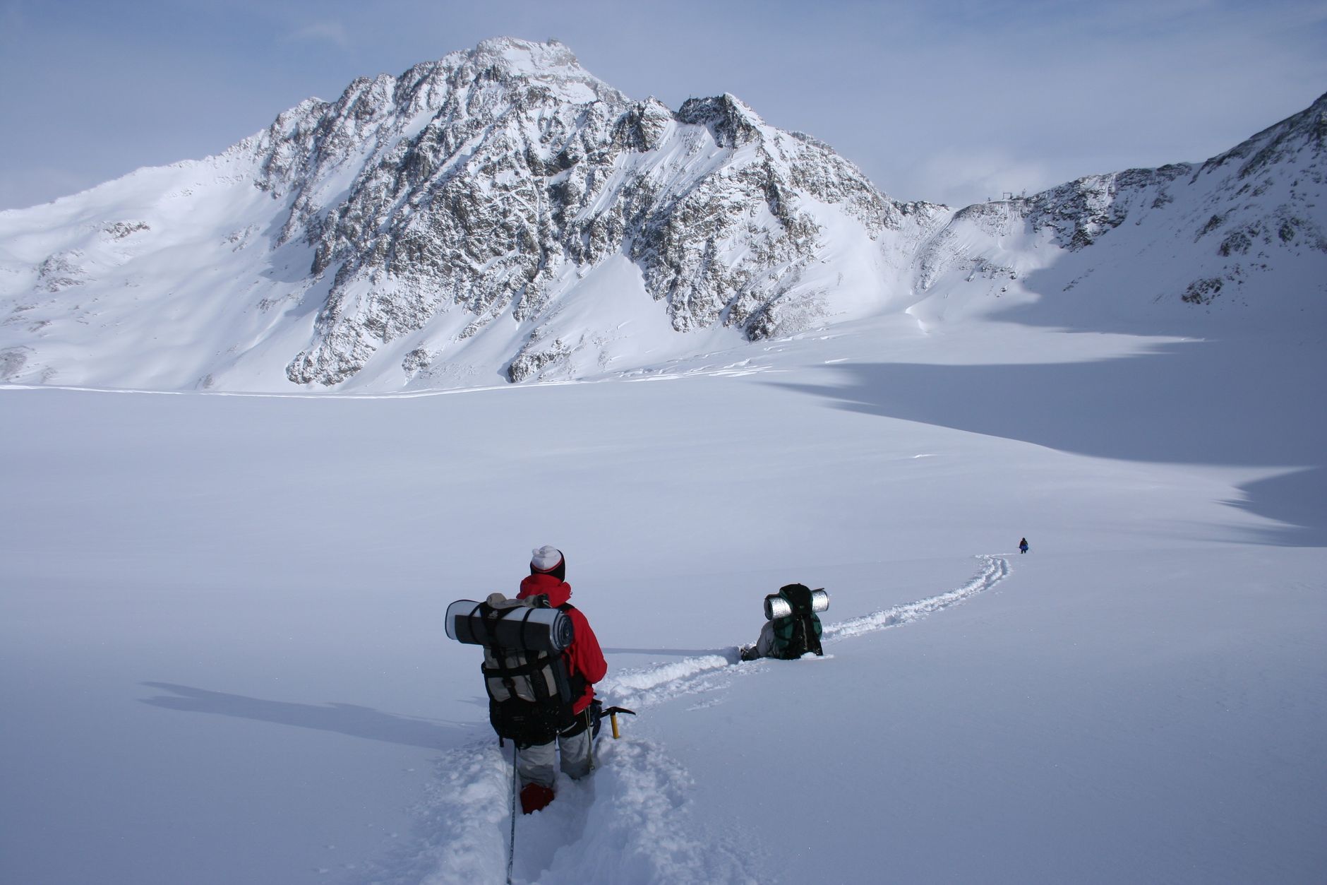 Hikers with backpacks journey through snowy mountain landscape, showcasing winter adventure.