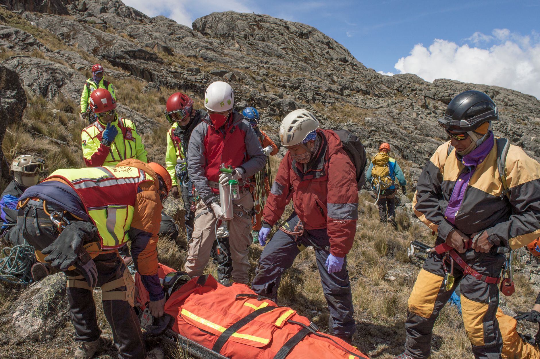 Rescue team aiding injured climber in rugged mountains of La Paz, Bolivia. Outdoor safety operation.
