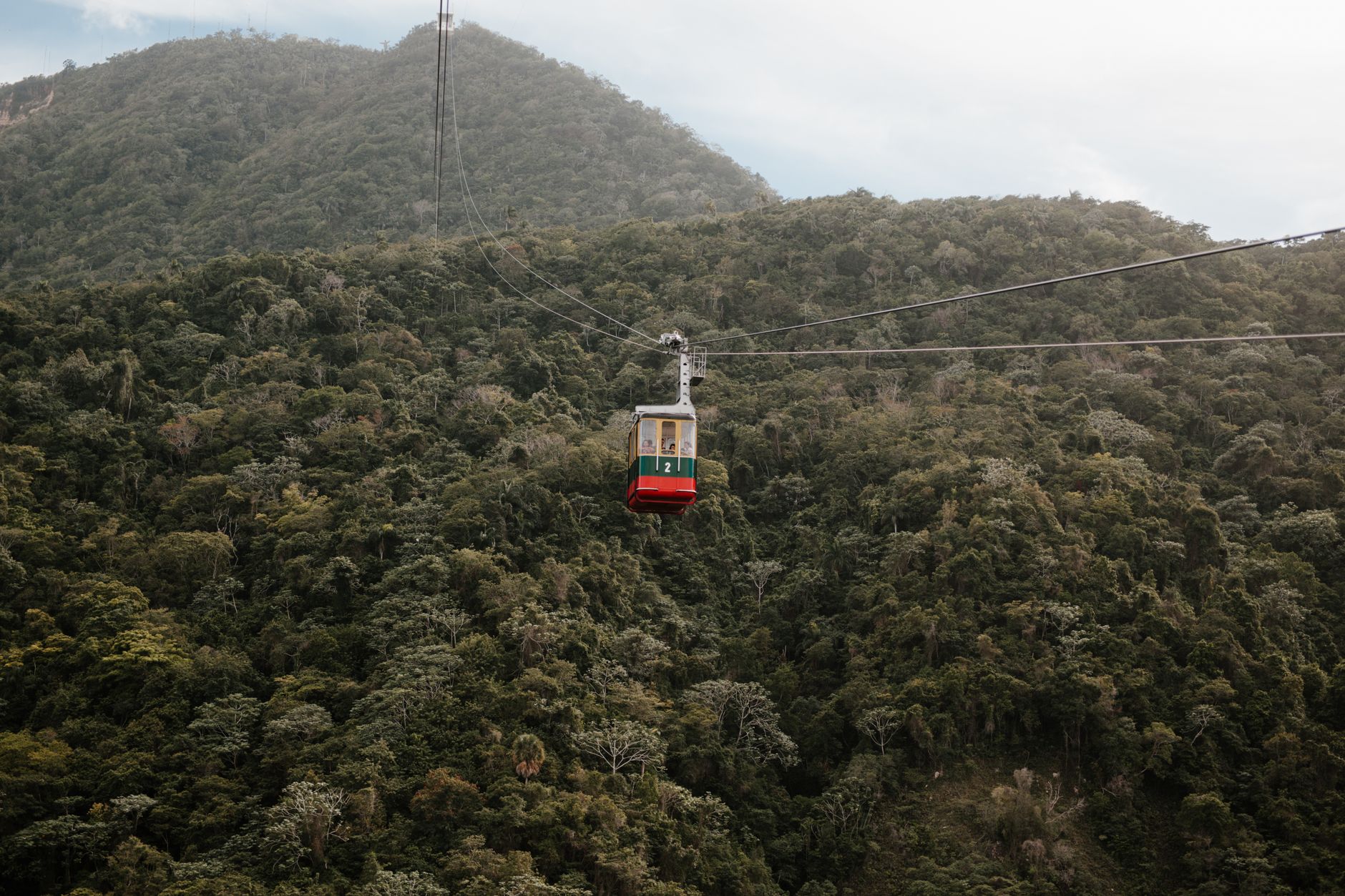 Experience a high-altitude cable car journey above verdant hills and dense wilderness.