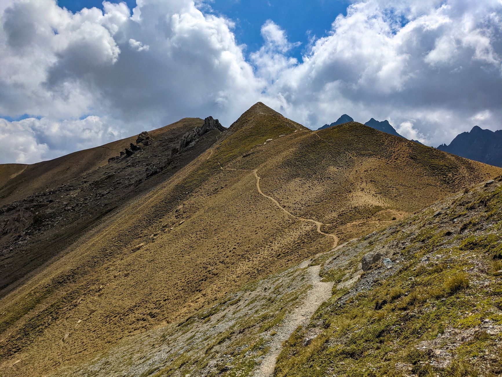 Breathtaking view of a winding mountain path beneath a dramatic, cloudy sky.