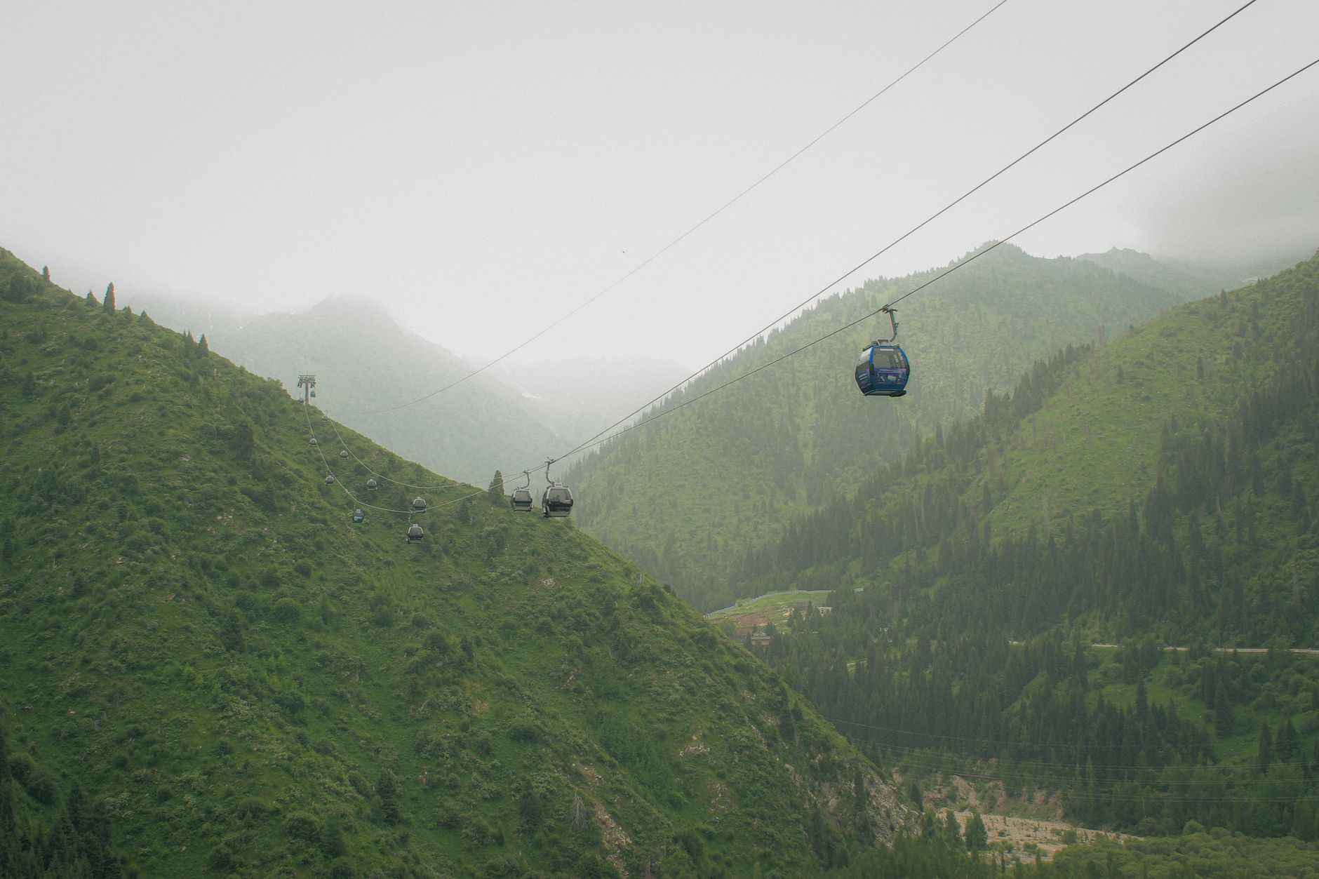 Experience a breathtaking cable car journey above green mountains enveloped in mist.