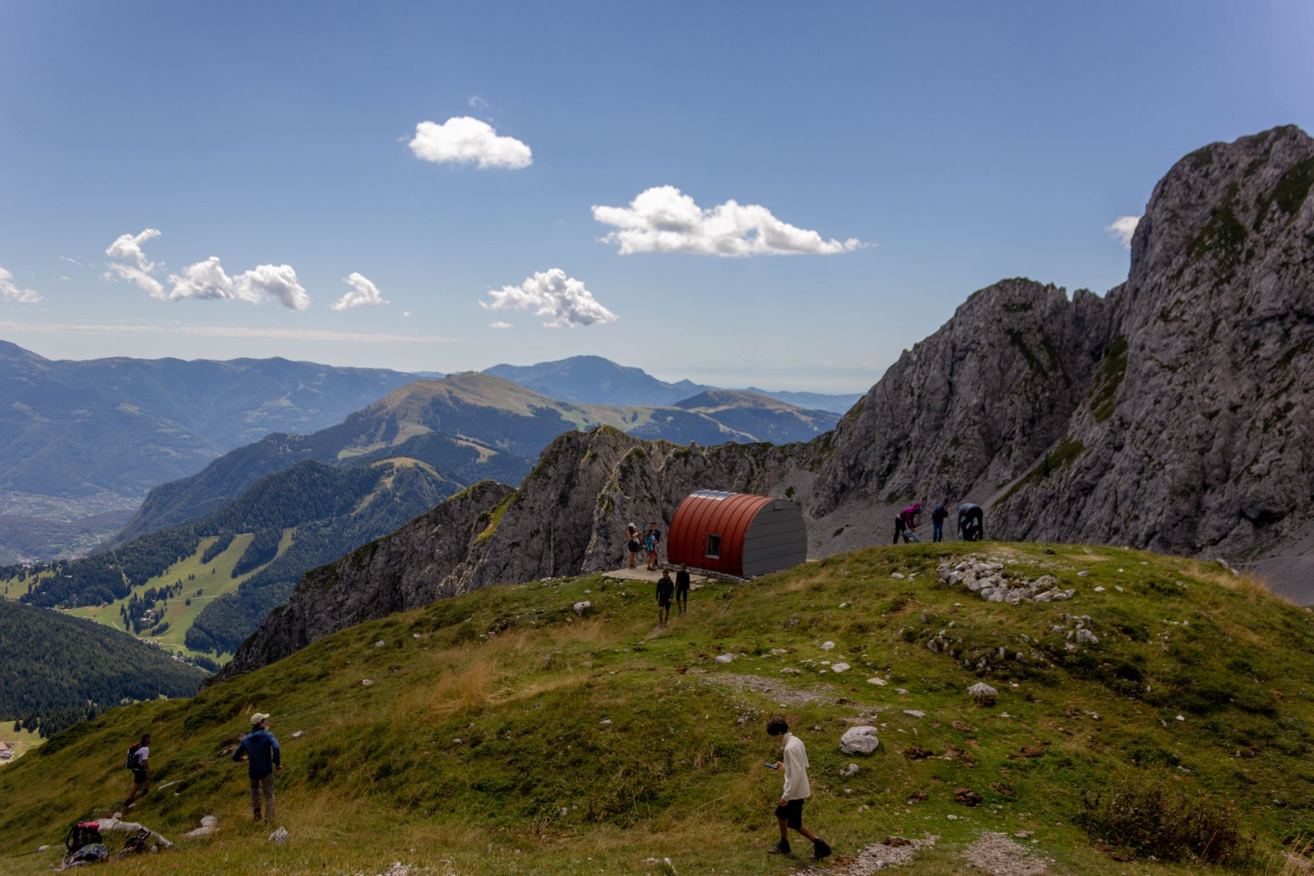 Group of hikers exploring a picturesque mountainous landscape with a red shelter.